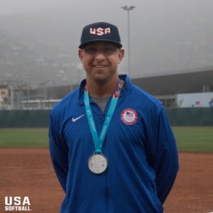 Athlete in USA jacket with silver medal at a baseball field.