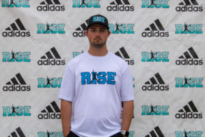 Man in a white Rise t-shirt and cap stands against a branded Adidas backdrop.